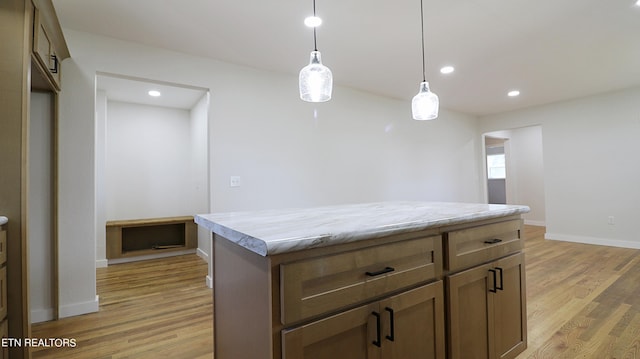 kitchen with hanging light fixtures, light hardwood / wood-style floors, and a center island