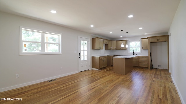 kitchen with hardwood / wood-style floors, sink, a kitchen island, and pendant lighting