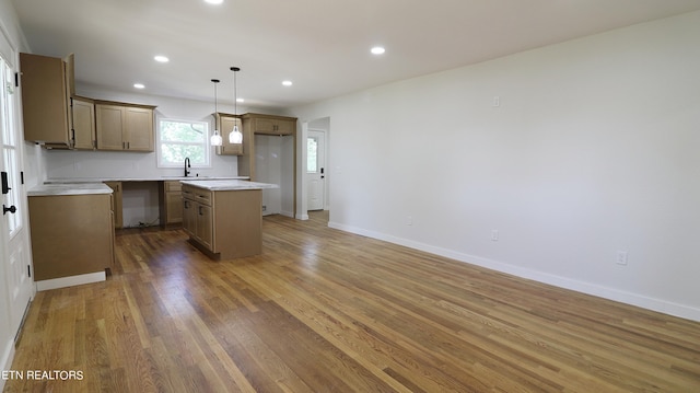 kitchen with hanging light fixtures, dark wood-type flooring, sink, and a center island