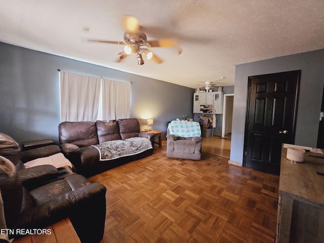 living room featuring a textured ceiling, ceiling fan, and dark parquet floors