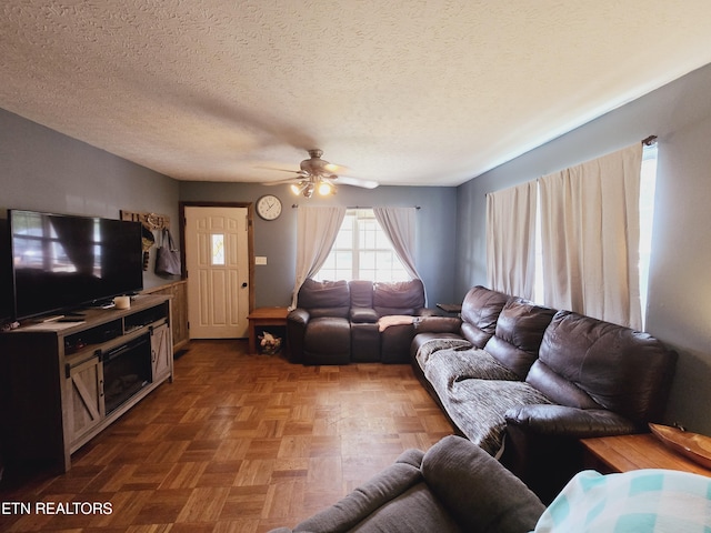 living room featuring a textured ceiling, ceiling fan, and parquet flooring