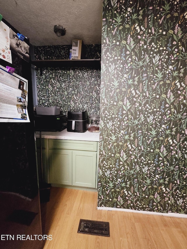 kitchen featuring light hardwood / wood-style floors, a textured ceiling, and green cabinetry