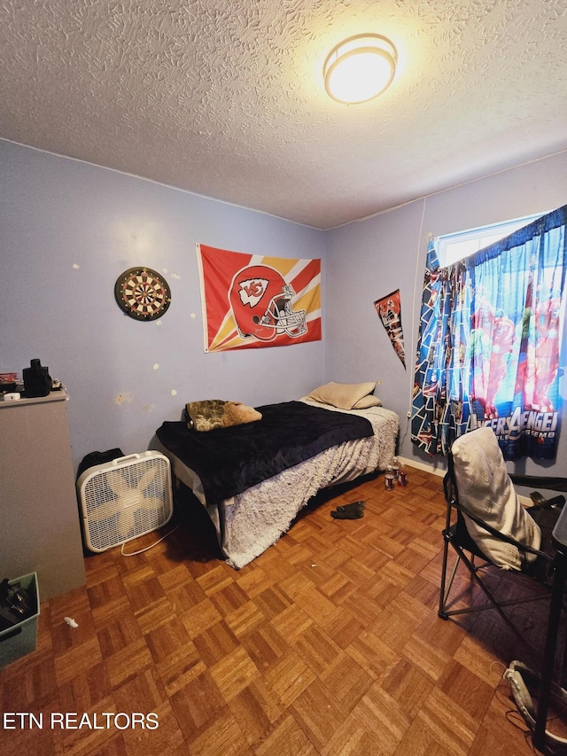 bedroom featuring parquet flooring and a textured ceiling