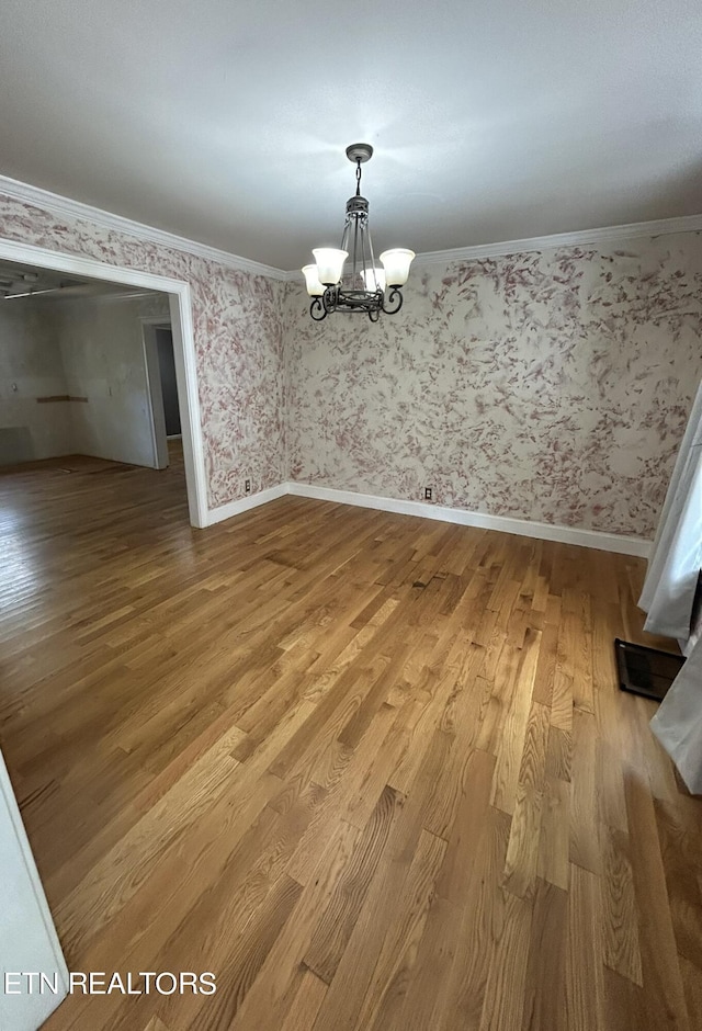 unfurnished dining area featuring light hardwood / wood-style floors, ornamental molding, and an inviting chandelier