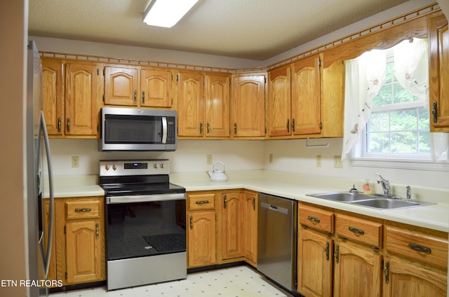 kitchen with a textured ceiling, stainless steel appliances, and sink