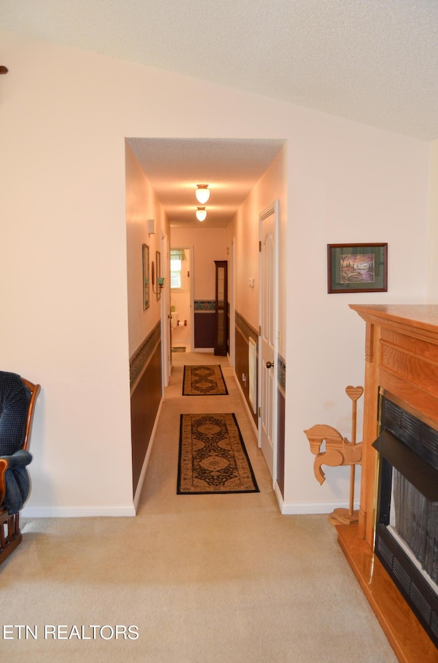 hall featuring a textured ceiling and light colored carpet