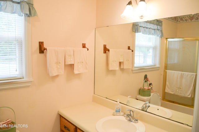 bathroom featuring a wealth of natural light, vanity, a shower with shower door, and toilet