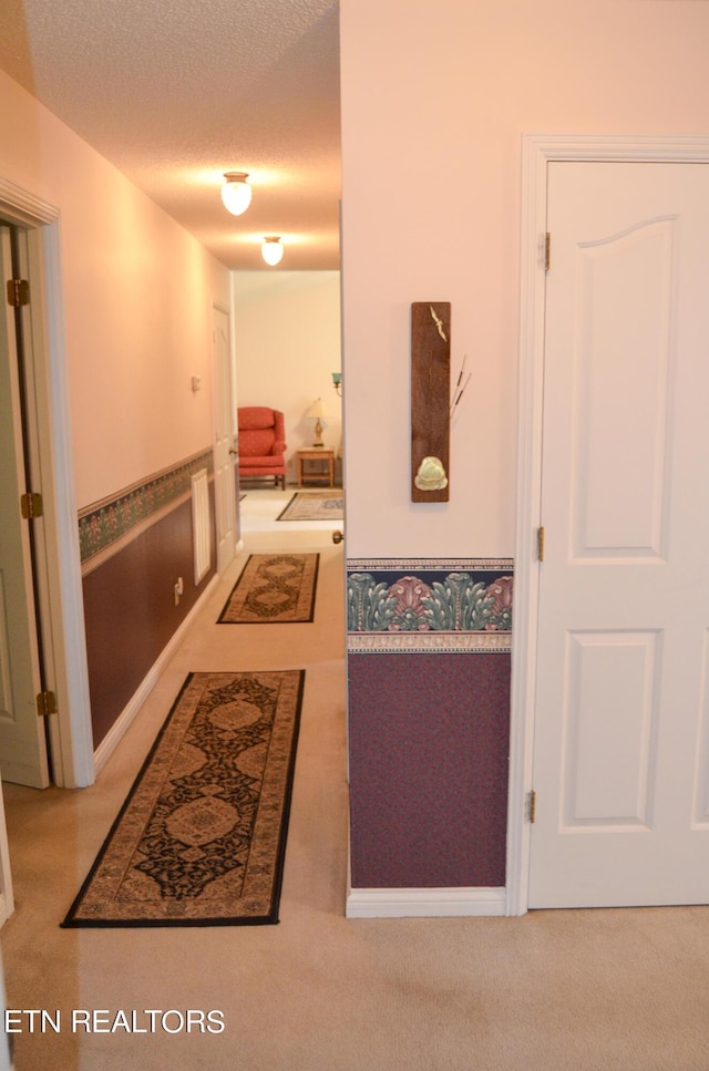 hall with carpet floors and a textured ceiling