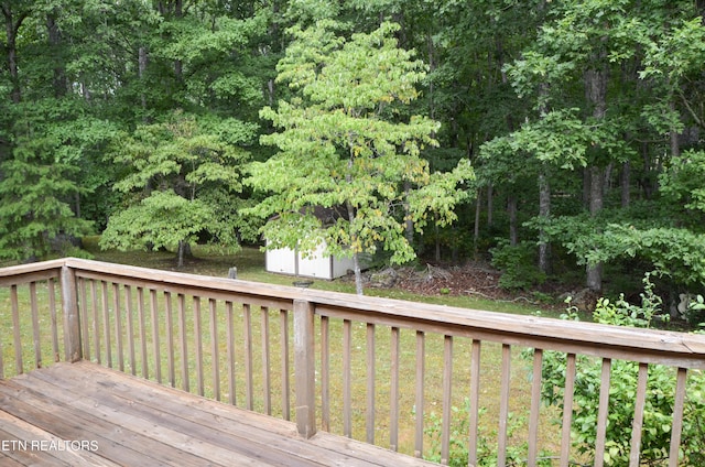 wooden terrace featuring a lawn and a storage shed