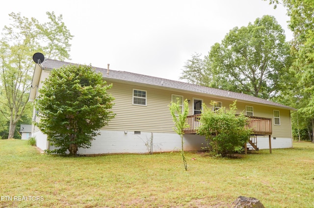 rear view of property featuring a wooden deck and a lawn