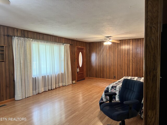 unfurnished room featuring ceiling fan, light hardwood / wood-style floors, and wooden walls