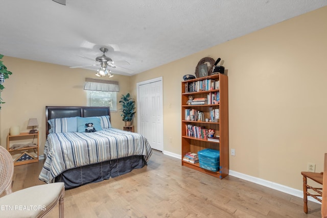 bedroom with ceiling fan, light hardwood / wood-style flooring, a closet, and a textured ceiling