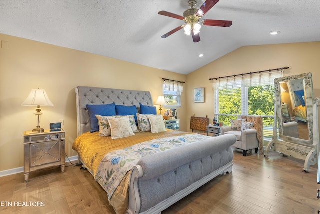 bedroom with ceiling fan, vaulted ceiling, a textured ceiling, and hardwood / wood-style flooring