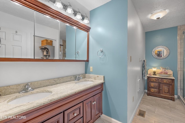 bathroom featuring a textured ceiling, a shower with door, tile patterned flooring, and vanity