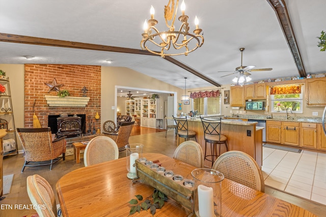 tiled dining space featuring ceiling fan with notable chandelier, vaulted ceiling with beams, sink, and a wood stove