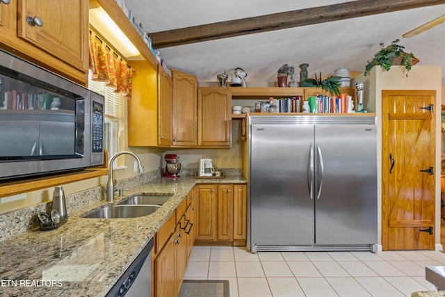 kitchen featuring built in appliances, beamed ceiling, light stone counters, sink, and light tile patterned flooring