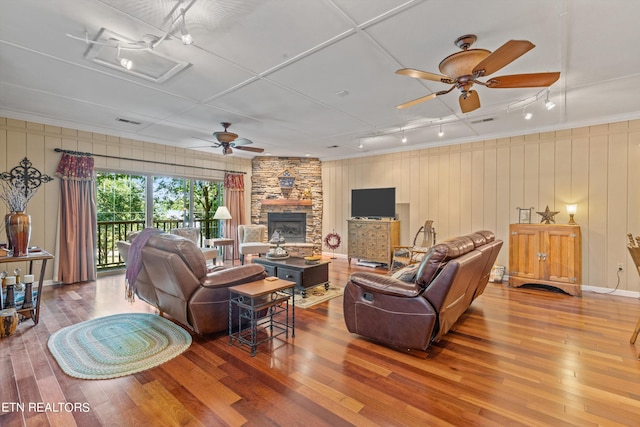 living room with ceiling fan, a fireplace, and hardwood / wood-style flooring