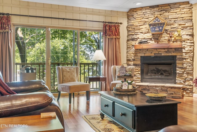 living area with ornamental molding, light hardwood / wood-style flooring, and a stone fireplace