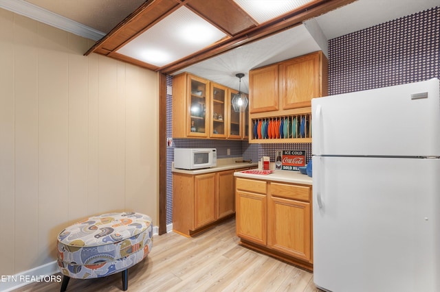 kitchen featuring white appliances, hanging light fixtures, and light hardwood / wood-style flooring