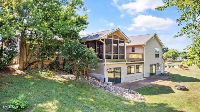 back of house with a fire pit, a wooden deck, a yard, and a sunroom