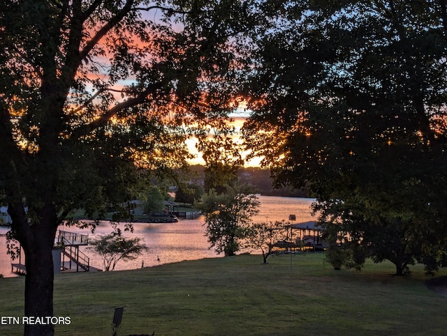 yard at dusk featuring a water view