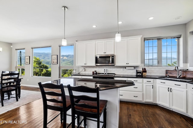 kitchen featuring white cabinetry, dark hardwood / wood-style floors, decorative light fixtures, sink, and a center island