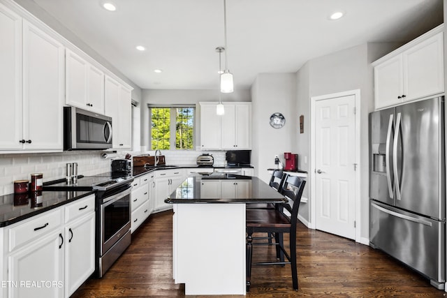 kitchen featuring decorative light fixtures, appliances with stainless steel finishes, white cabinetry, and a kitchen island