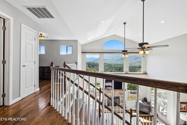 corridor with a wealth of natural light, lofted ceiling, and dark hardwood / wood-style floors