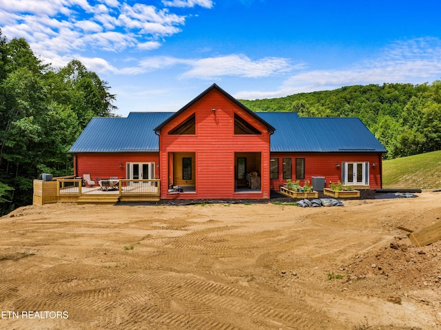 back of house featuring french doors, a wooden deck, and central air condition unit