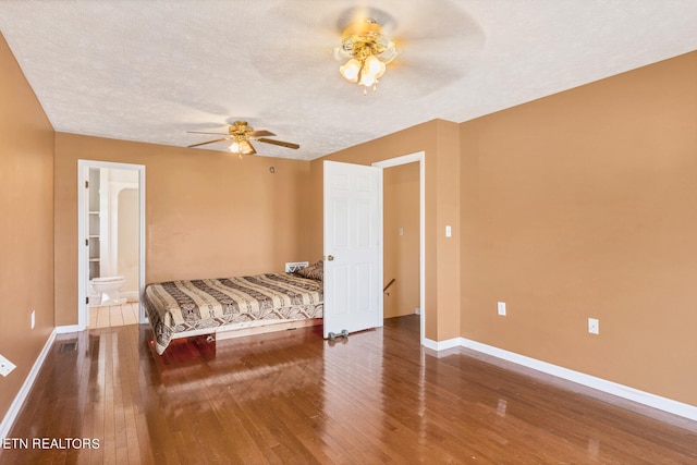 bedroom with a textured ceiling, ceiling fan, connected bathroom, and hardwood / wood-style floors