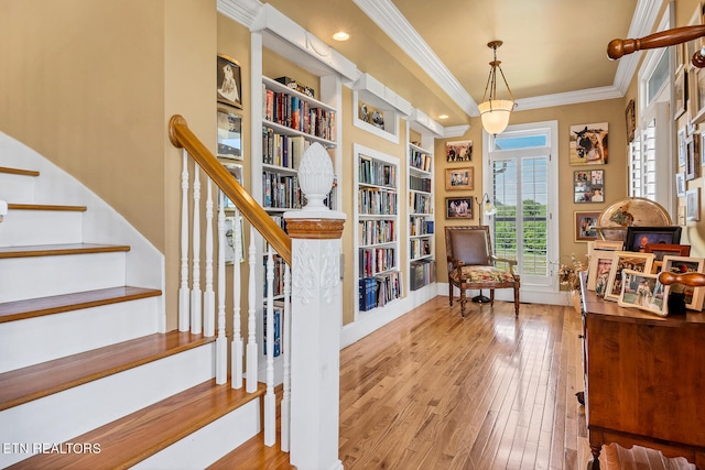 living area featuring built in shelves, light hardwood / wood-style flooring, and ornamental molding