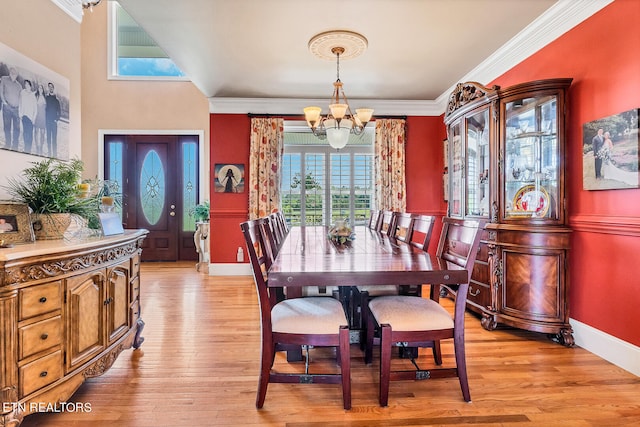 dining space with a notable chandelier, light wood-type flooring, and ornamental molding