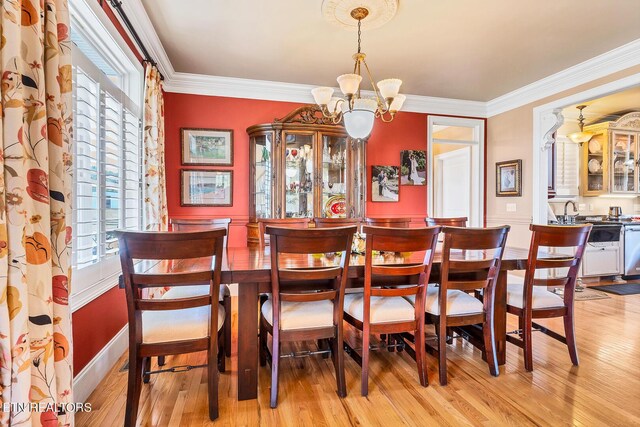 dining space with light hardwood / wood-style flooring, an inviting chandelier, and crown molding