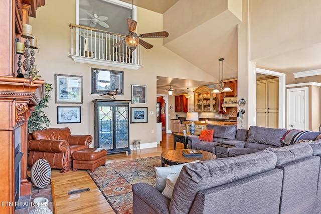 living room with ceiling fan, hardwood / wood-style flooring, and a towering ceiling