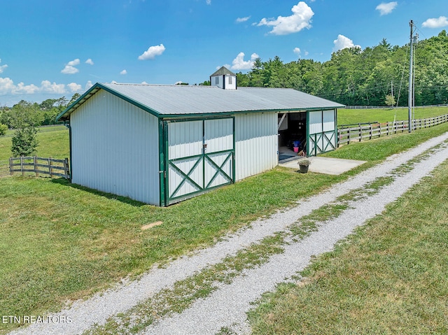 view of outdoor structure featuring a rural view and a lawn