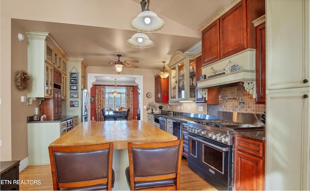 kitchen with light hardwood / wood-style floors, range with two ovens, custom exhaust hood, and ceiling fan