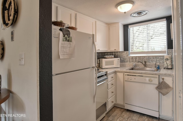 kitchen featuring white appliances, backsplash, white cabinetry, and sink