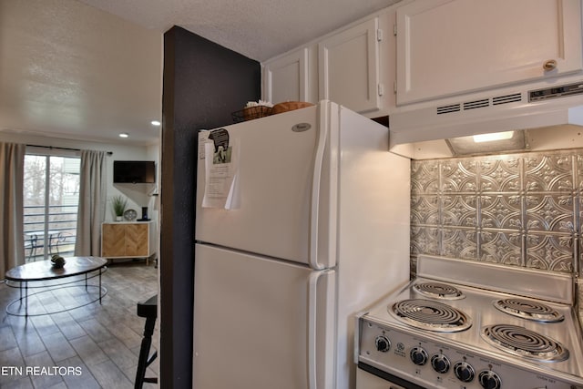 kitchen with white cabinetry, stovetop, white fridge, a textured ceiling, and hardwood / wood-style flooring