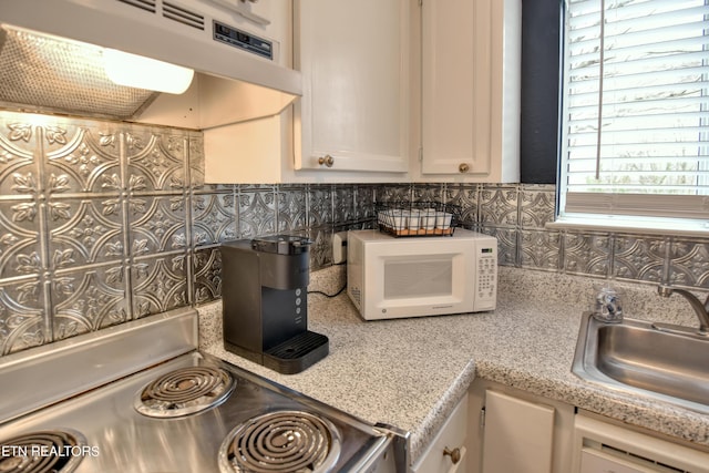 kitchen featuring light stone countertops, stove, and sink