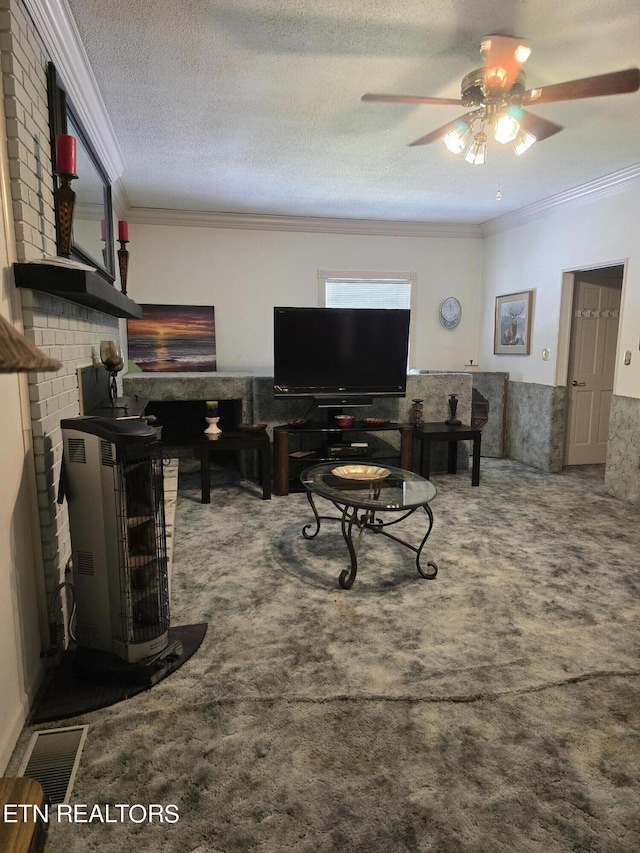 living room featuring ceiling fan, ornamental molding, a textured ceiling, and carpet floors