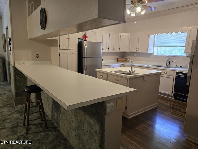 kitchen featuring a kitchen bar, stainless steel fridge, kitchen peninsula, crown molding, and white cabinets