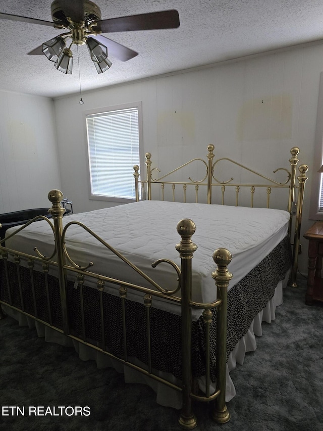 bedroom featuring ceiling fan, a textured ceiling, and dark colored carpet