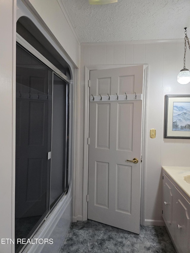 bathroom with vanity, a shower with shower door, and a textured ceiling