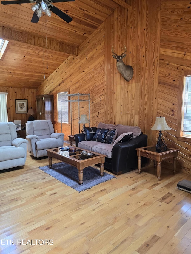 living room featuring light wood-type flooring, wooden walls, ceiling fan, and wooden ceiling