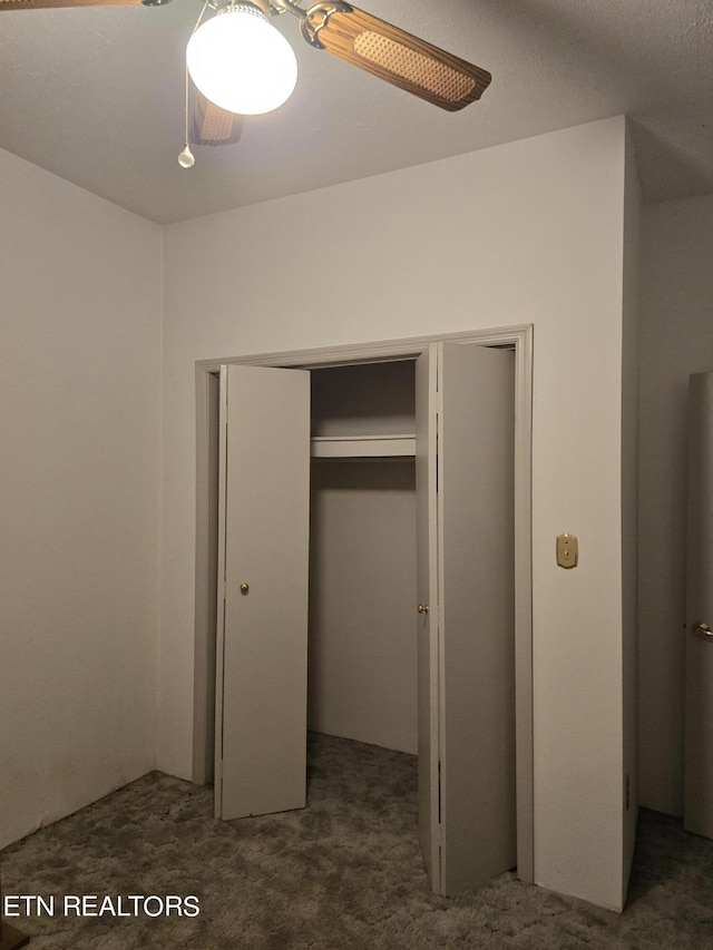 unfurnished bedroom with ceiling fan, a closet, and dark colored carpet