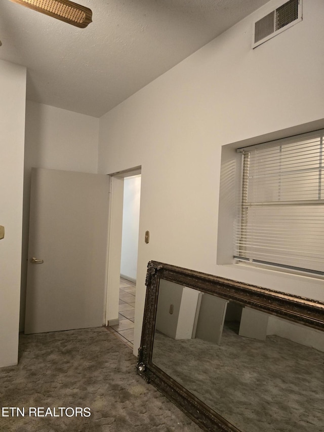 hall with carpet flooring and a textured ceiling