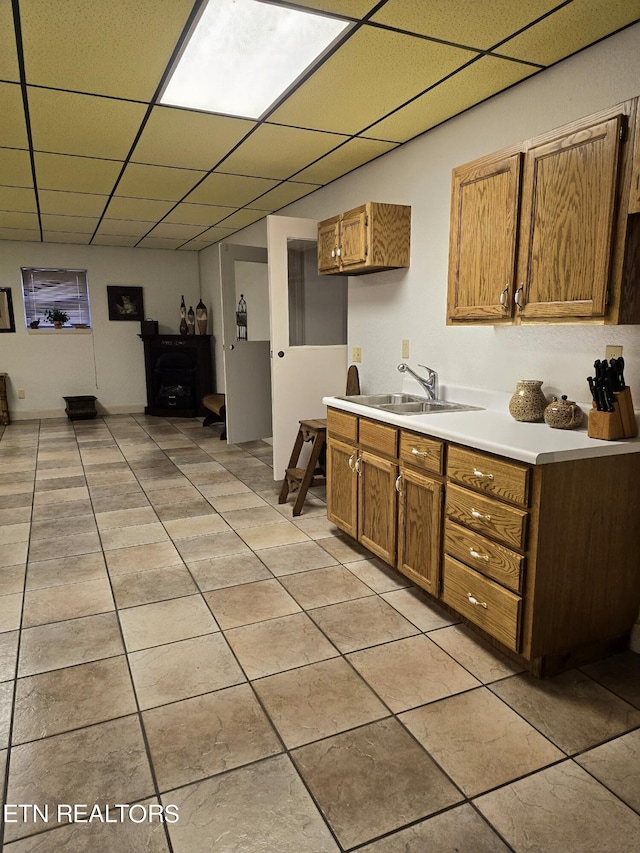 kitchen featuring light tile patterned floors, a paneled ceiling, and sink