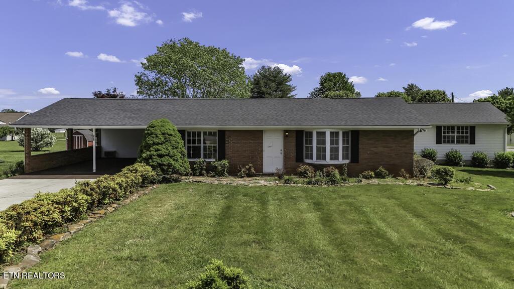 ranch-style home featuring an attached carport, concrete driveway, and a front yard