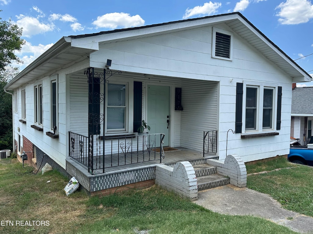 bungalow-style house with a front yard, a porch, and central AC