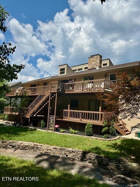 rear view of property with a deck, a chimney, and stairway